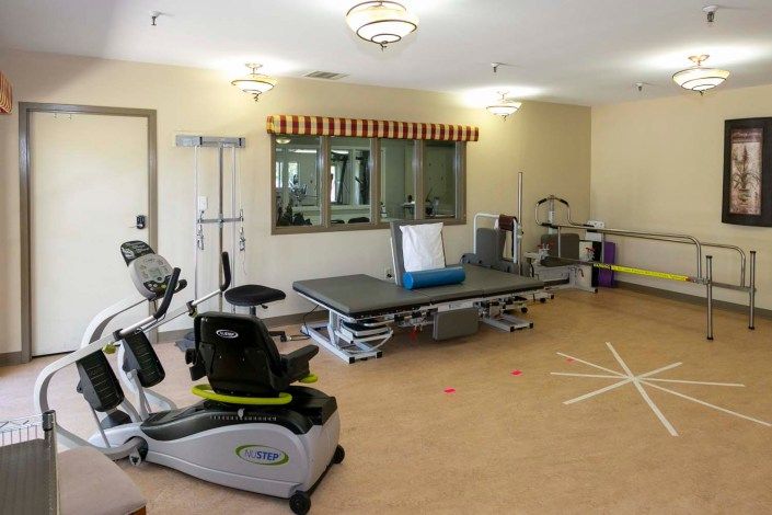 A well-equipped physical therapy and rehabilitation room with various exercise machines and treatment tables.