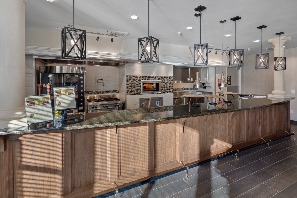 A modern kitchen with wood cabinets, a large island counter, and stainless steel appliances.
