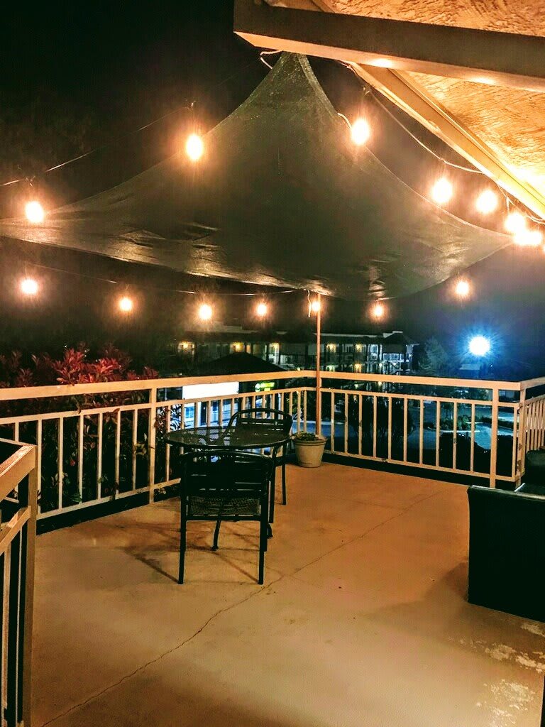 A cozy outdoor patio at night, illuminated by warm string lights.