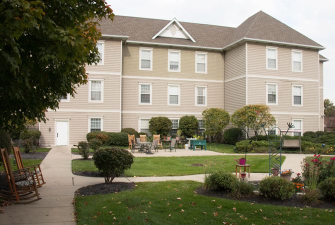 A three-story residential building with well-maintained landscaping and outdoor seating.