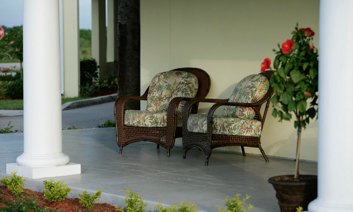 A cozy patio setup with wicker chairs and floral cushions on a porch.
