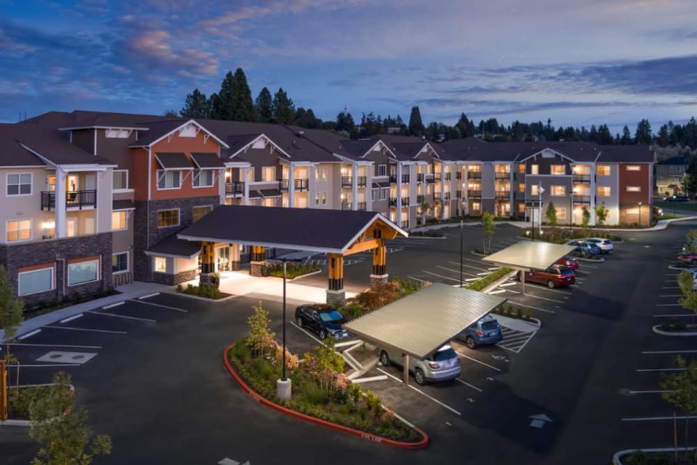 A well-lit residential apartment complex with a parking lot in the evening.