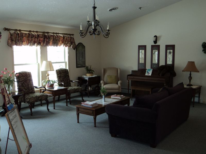 A cozy living room with a sofa, chairs, coffee tables, and a chandelier.