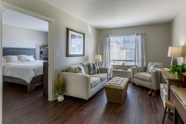 A modern and bright living room with a sofa, armchair, and large window.