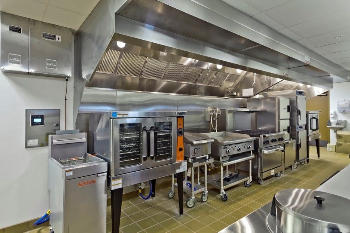 A spacious commercial kitchen equipped with stainless steel appliances and an industrial ventilation system.