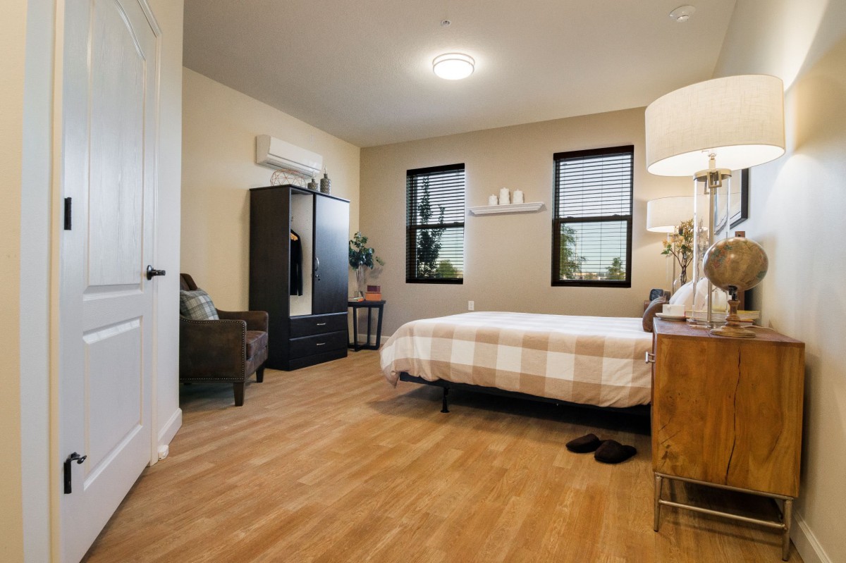A modern and cozy bedroom featuring a comfortable bed with a checkered duvet, wooden flooring, and stylish decor.
