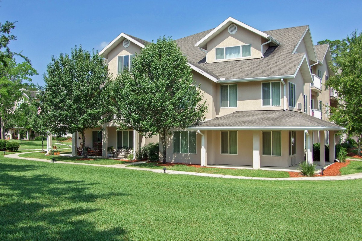 A suburban residential building with a well-kept lawn and trees in front.