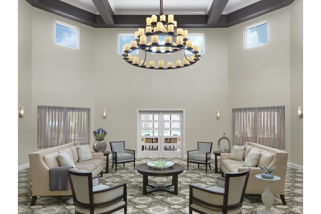 A spacious and elegant living room with a central chandelier and comfortable seating arrangement.