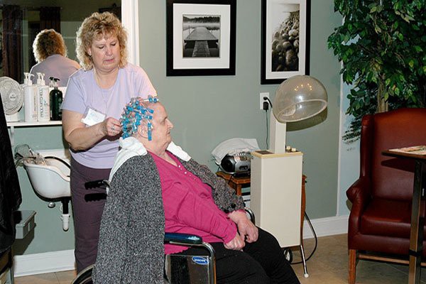 An older woman gets her hair styled with perm rods at a hair salon.