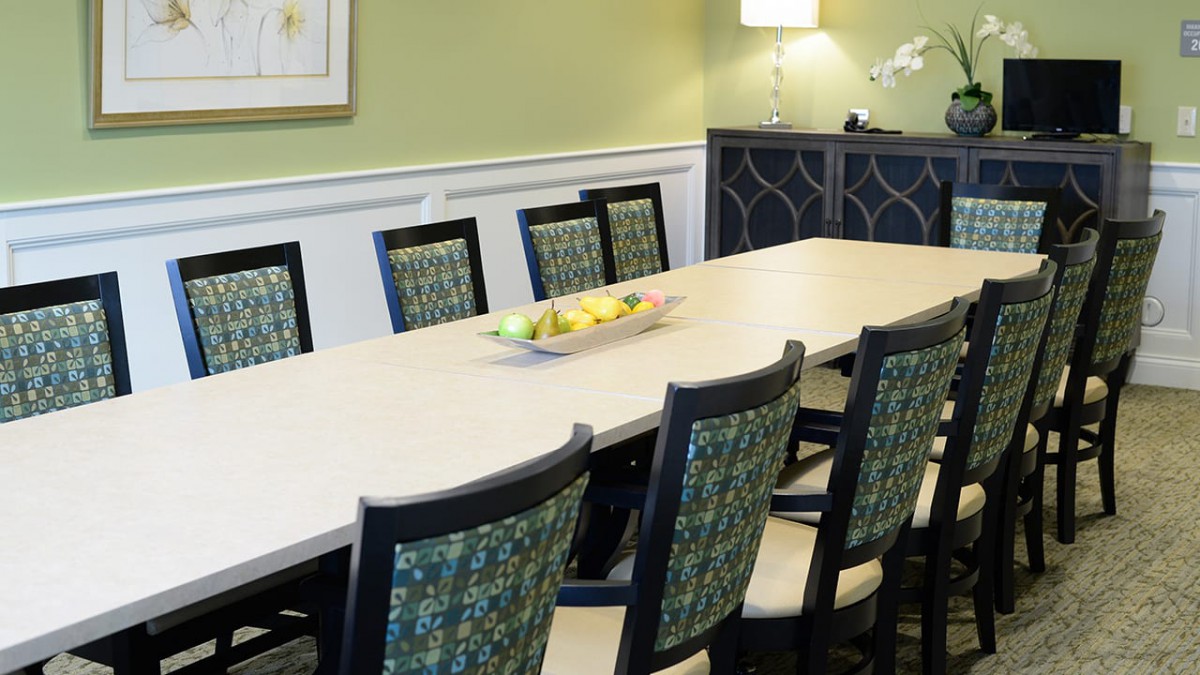 A modern dining room with a long table, stylish chairs, and a decorative light fixture.
