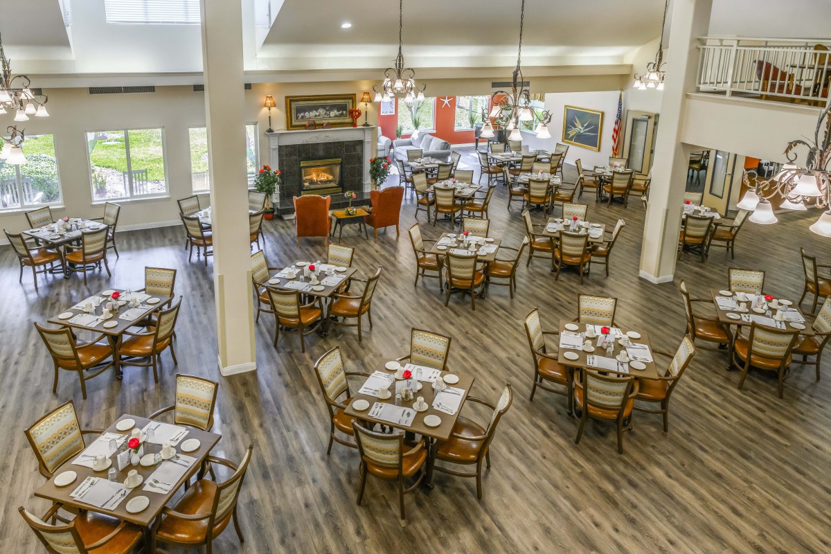 A spacious dining area with neatly arranged tables and chairs, featuring elegant decor and wooden flooring.