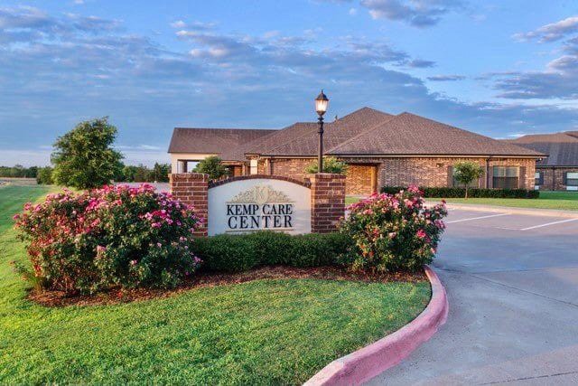 A building with a well-manicured garden and a sign reading 'EMPCARE CENTER' at the entrance.