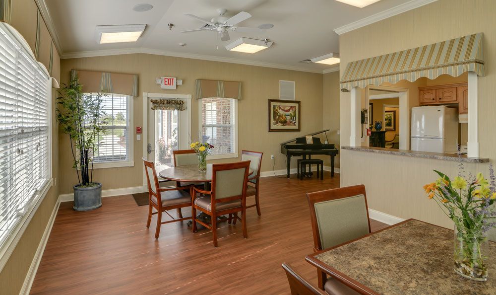 A cozy dining area with tables, chairs, and a piano by the window.