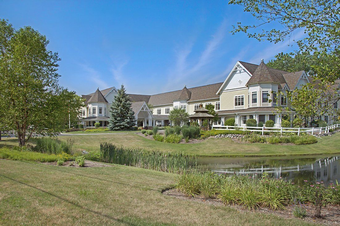 A picturesque residential house with a pond and landscaped surroundings under a clear blue sky.