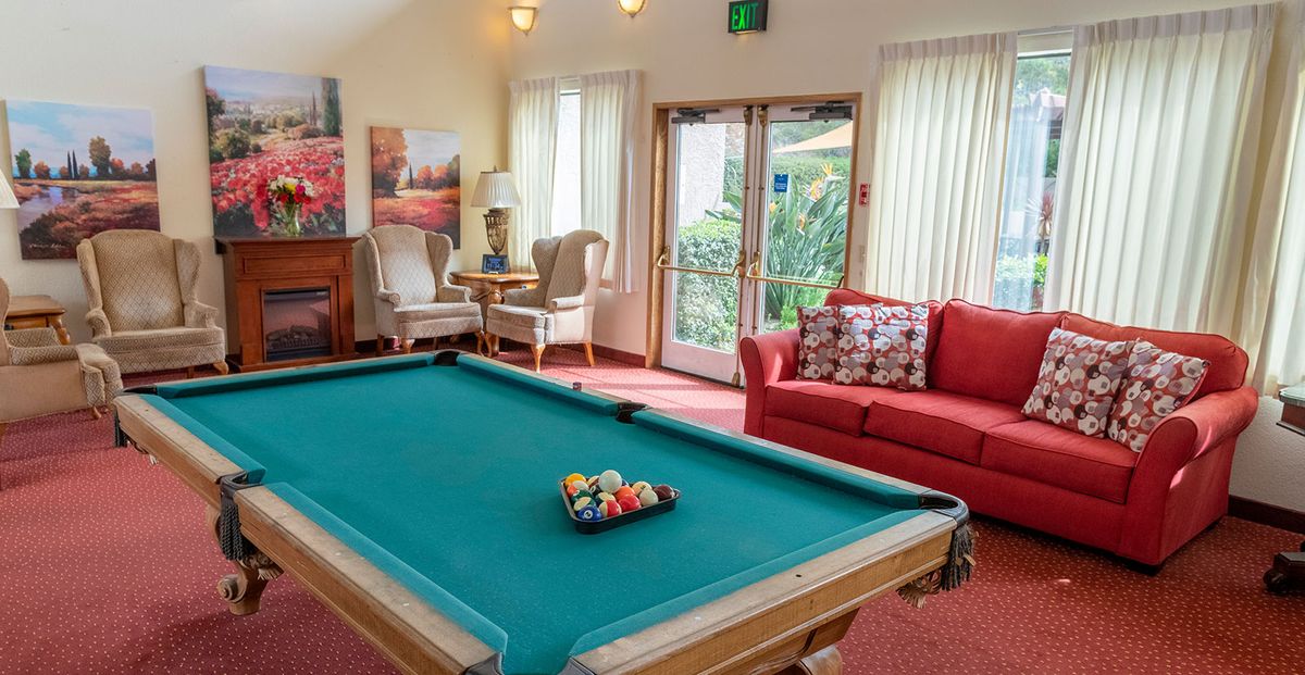A cozy living room with a pool table, comfortable seating, and warm lighting.