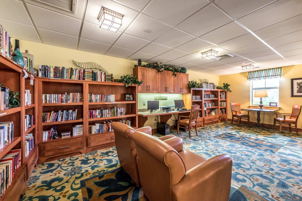 A cozy library space with bookshelves, comfortable seating, and computer workstations.