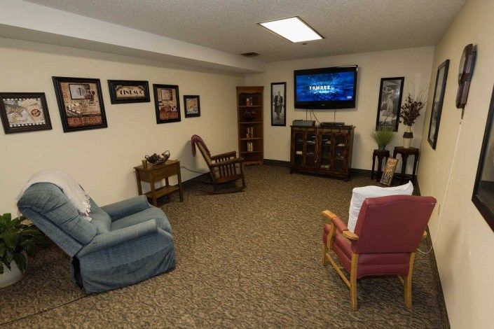 A cozy living room with various seating options and a wall-mounted TV.