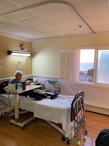 A patient room in a hospital with a bed, a table, and natural light coming through the window.