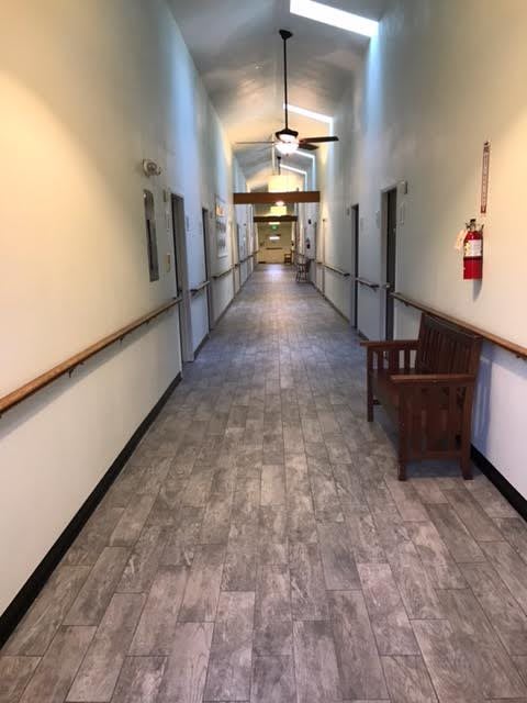 A long, well-lit hallway with a bench and fire extinguisher on the side.