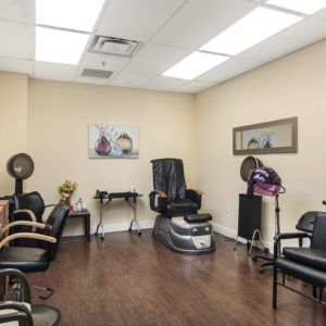 Interior view of a hair salon featuring styling chairs, mirrors, and hair drying equipment.