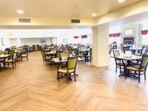 A spacious dining room with neatly arranged tables and chairs on a wooden floor.