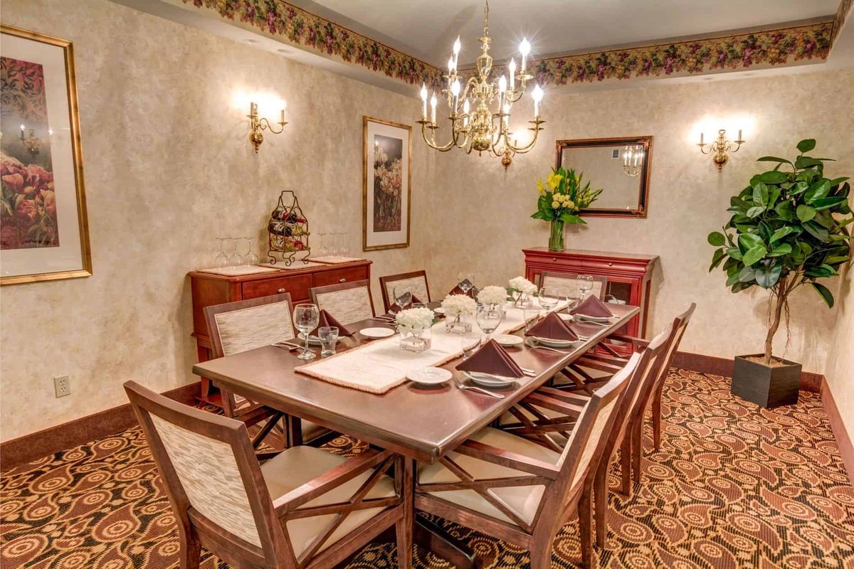 An elegant dining room with a large table, set for a meal, under a sparkling chandelier.