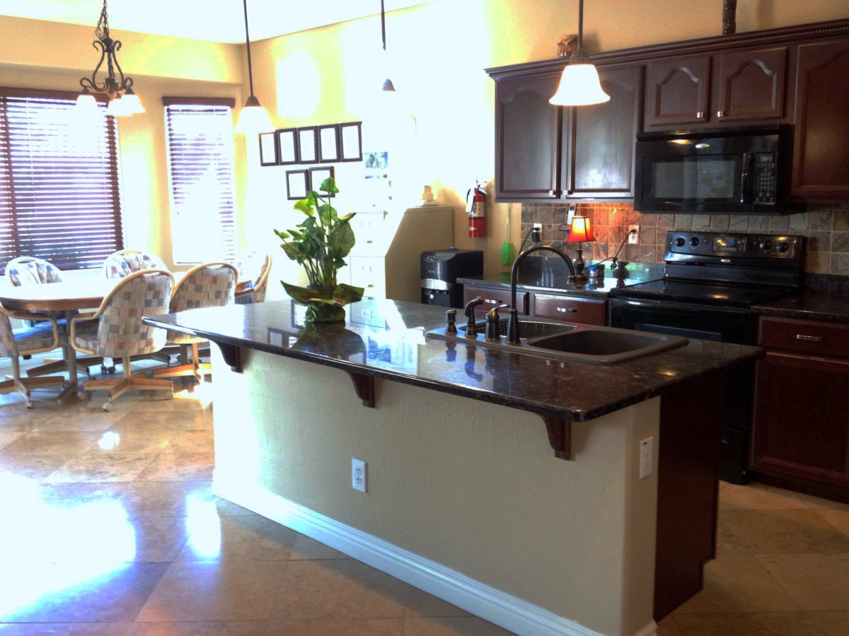 A modern kitchen with a central island and attached dining area.