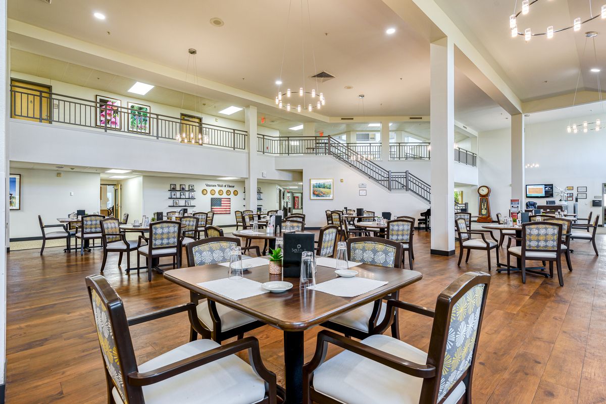 A modern dining area with neatly arranged tables and chairs, featuring elegant lighting and a spacious interior.