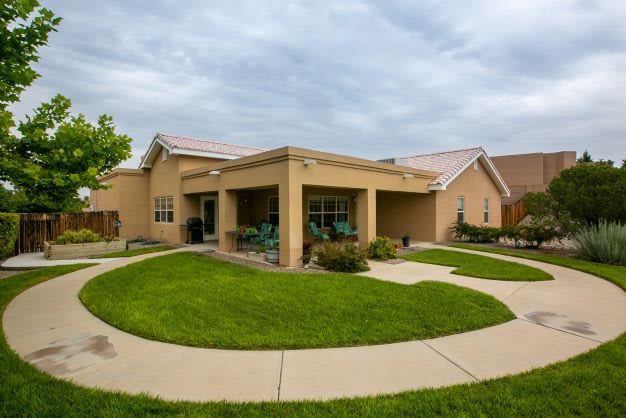 A suburban house with a well-maintained lawn and pathway under a cloudy sky.