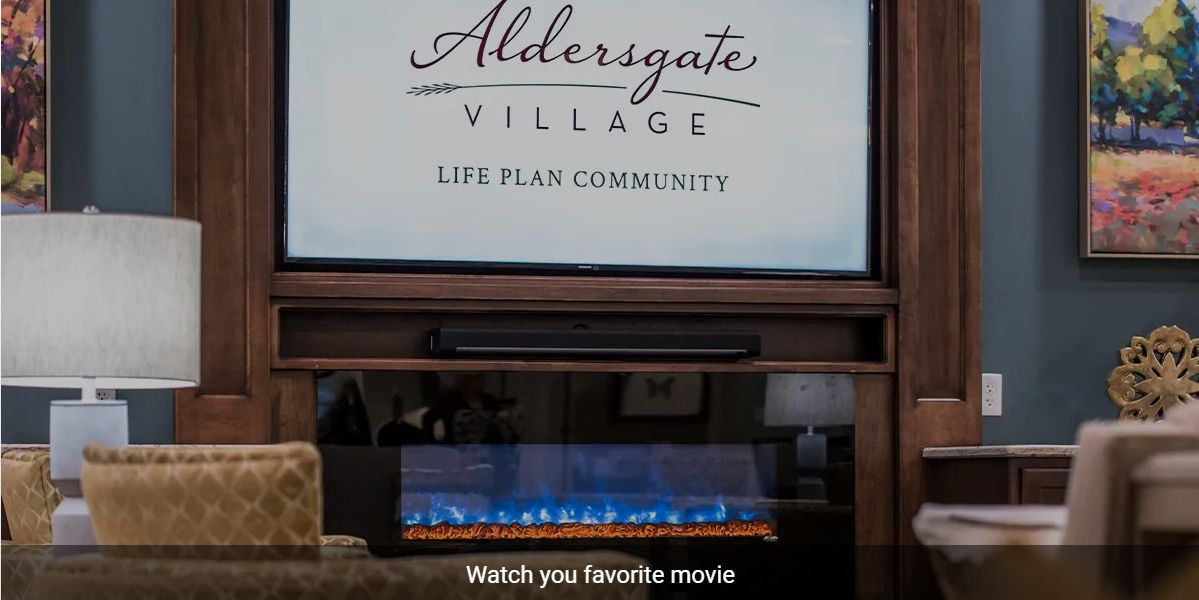 An advertisement for Aldersgate Village Life Plan Community displayed above a cozy fireplace.