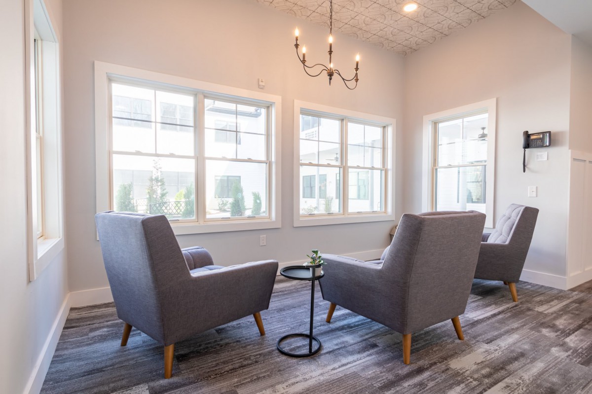 A modern, minimalist living room with comfortable chairs and large windows.