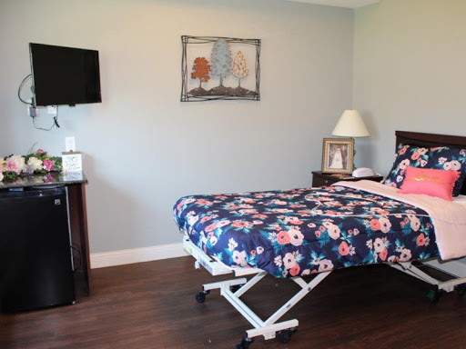 A cozy bedroom featuring a floral patterned bedspread, a bedside lamp, and a wall-mounted television.