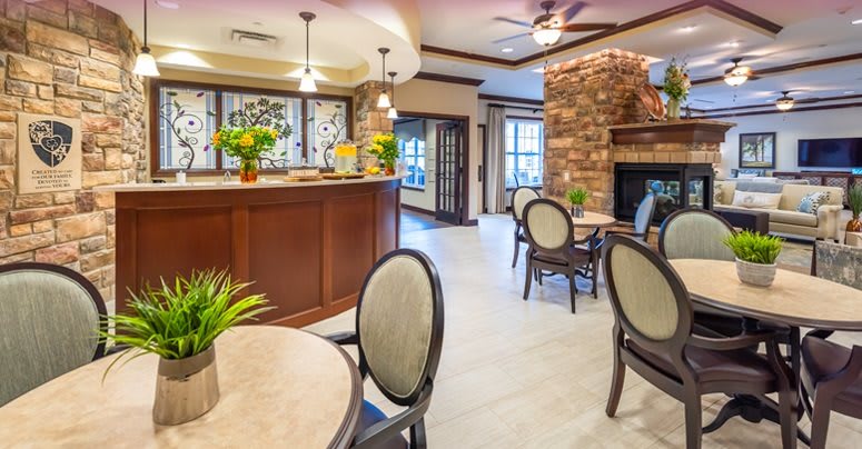 A cozy lobby area with tables and chairs, featuring a reception desk and a brick fireplace.