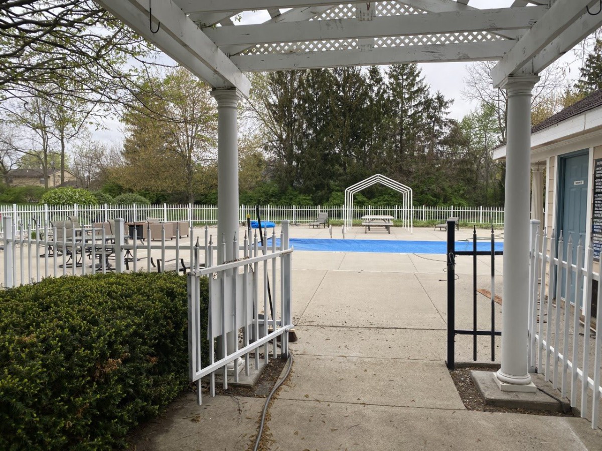 An empty outdoor pool area surrounded by trees and a gazebo.
