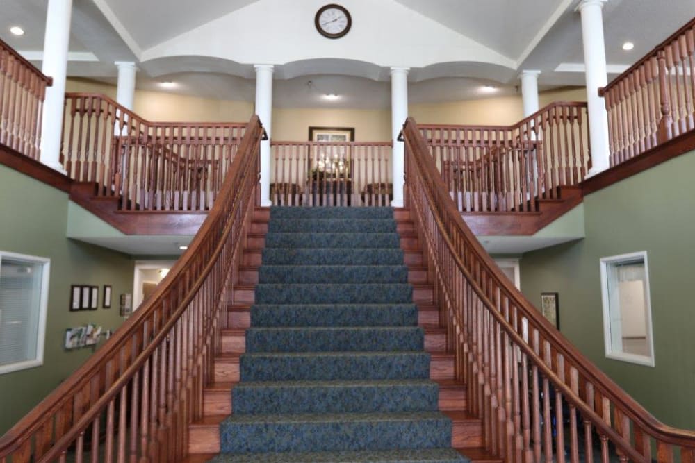 A grand staircase with wooden railings and carpeted steps in a spacious interior.