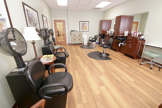 An empty hair salon with chairs, mirrors, and a waiting area.
