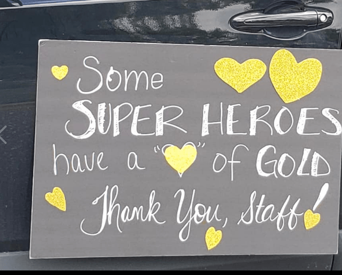 A heartfelt handwritten sign expressing gratitude to staff with the message 'Some super heroes have a heart of gold. Thank you, staff.'