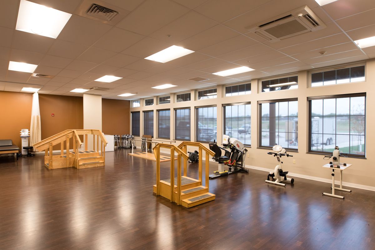 A spacious rehabilitation room equipped with exercise equipment and large windows.