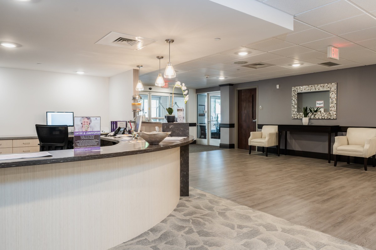 A modern reception area featuring a curved desk, contemporary lighting fixtures, and comfortable seating in a neutral color palette.