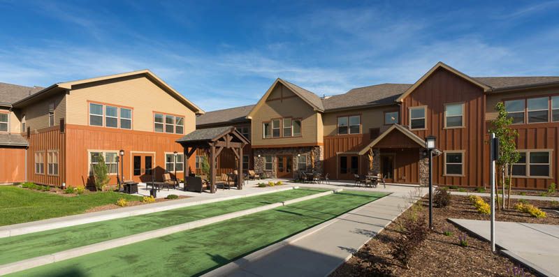 A modern residential building with a landscaped yard and clear blue skies.
