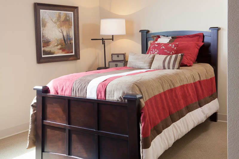 A cozy bedroom with a neatly made bed, warm colors, and decorative accents.