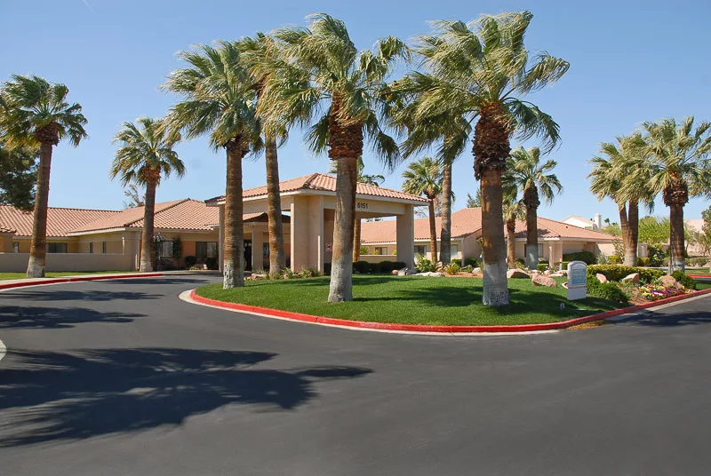 A hotel entrance surrounded by palm trees with a circular driveway.