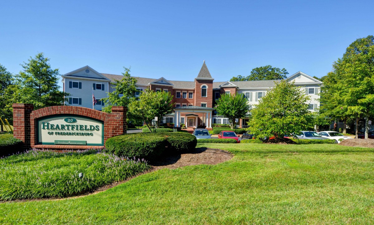 A residential building with well-maintained landscaping and a sign out front.