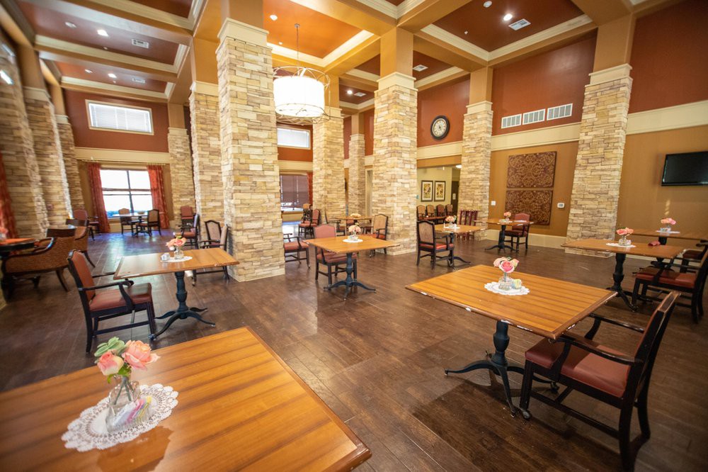 A modern restaurant dining area featuring wooden tables, stone columns, and elegant decor.