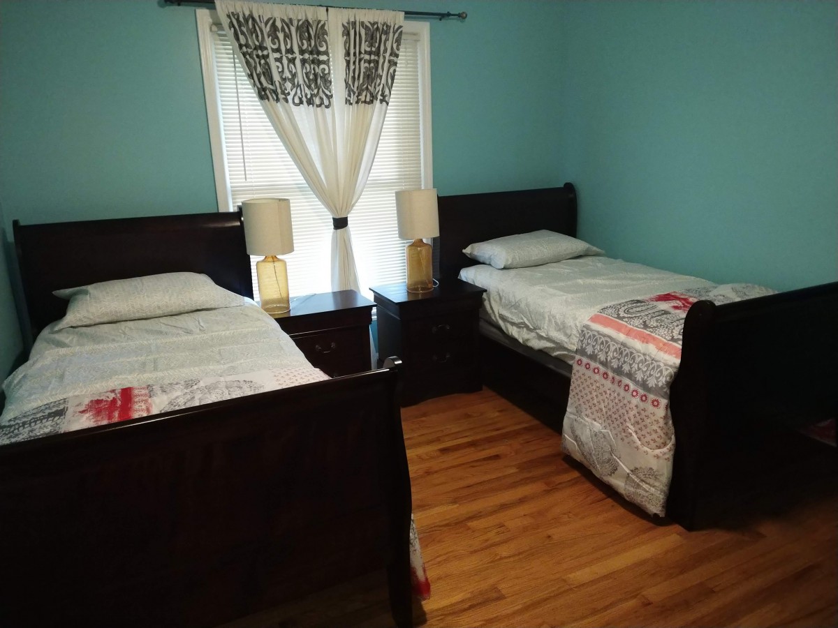 A cozy bedroom with twin beds, a nightstand, and decorative curtains.