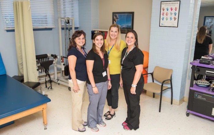 A group of women posing together in an office setting.