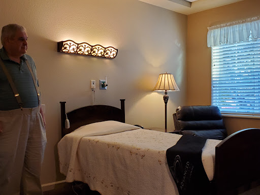 A cozy and well-lit bedroom featuring a neatly made bed, a comfortable chair, and warm lighting.