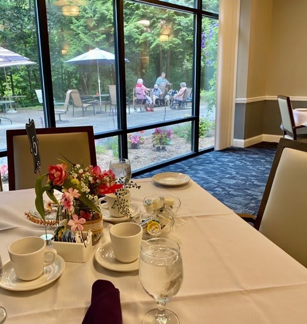 A elegantly set dining table near large windows with a view of an outdoor patio.