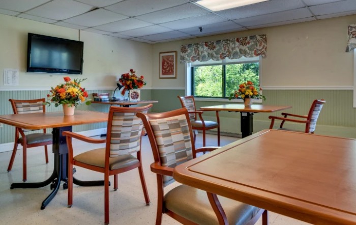 A well-lit dining area with tables and chairs, adorned with floral arrangements.
