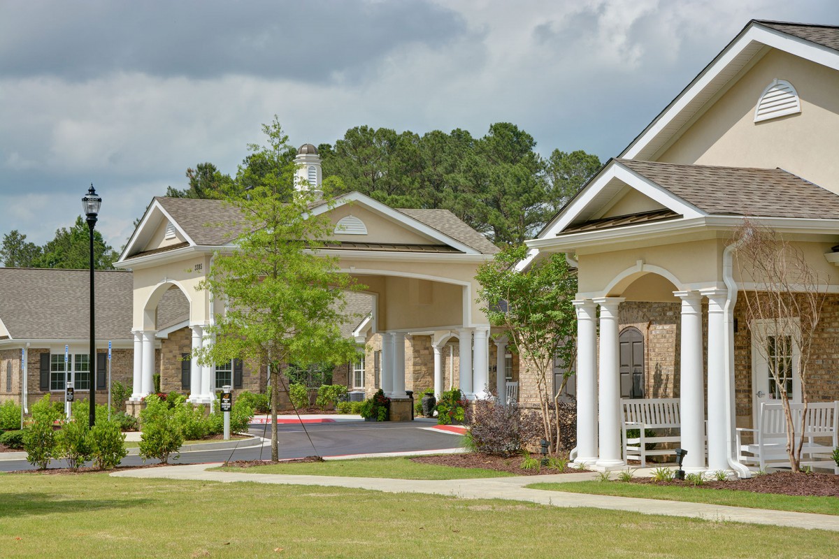 A scenic view of residential buildings with lush greenery and a spacious lawn.